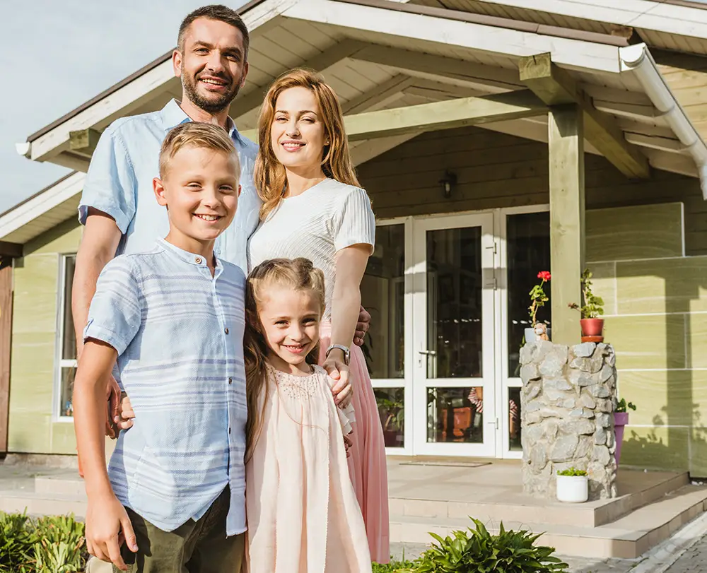 Happy family smiling outside their home, representing homeowners and life coverage across Metro Detroit service areas by Kange Insurance Agency.